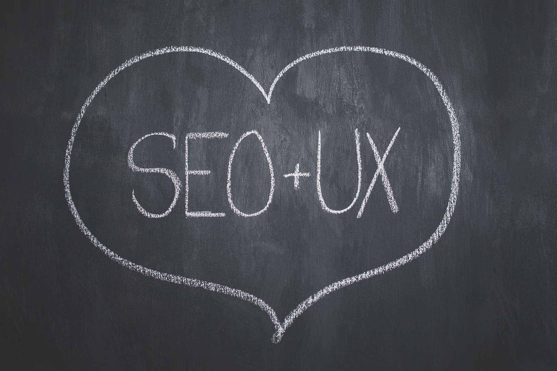 Heart containing the words SEO and UX on a blackboard